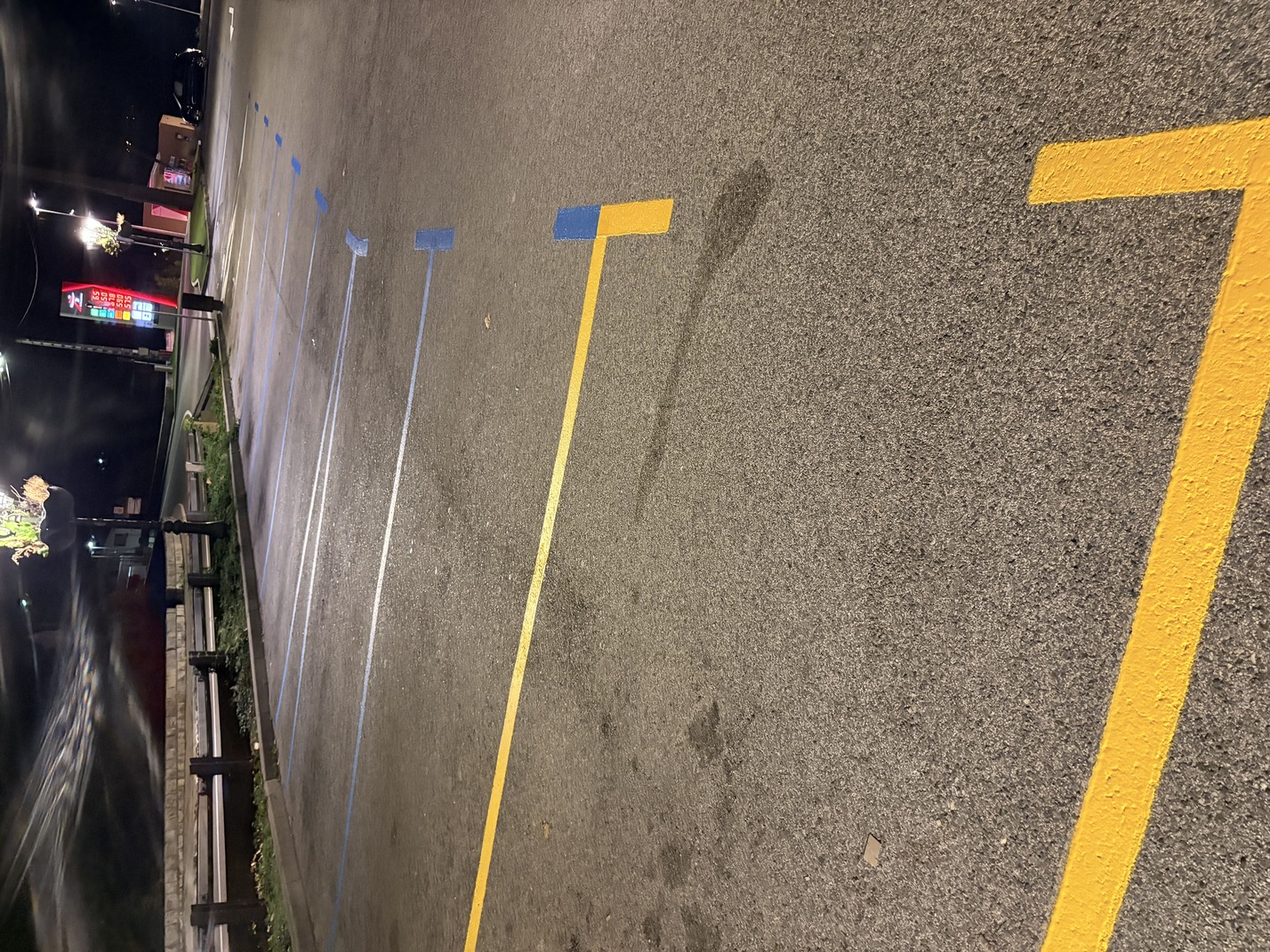 Marquage passage piéton, places de stationnement bleues à durée limité sur enrobé de nuit et places jaunes livraison